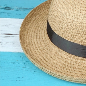 Close-up of fine woven straw texture and black satin ribbon detail on a summer sun hat