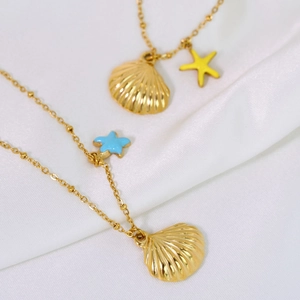 Minimalist stainless steel 14K gold shell and starfish pendant necklace on white satin fabric