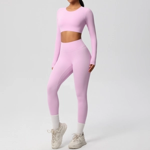 Pink yoga set featuring a long sleeve crop top and high waist leggings in studio setting
