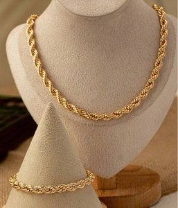Detailed view of gold rope chain necklace and bracelet set on jewelry display stands