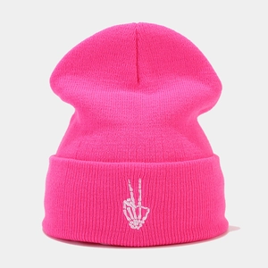 Gros plan détaillé du bonnet en maille rose avec broderie main de squelette blanche