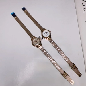Detailed macro view of two rose gold mesh band quartz watches on a magazine page
