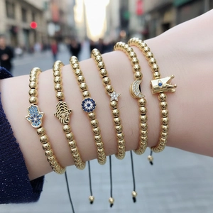 Detailed view of layered gold beaded bracelets with blue evil eye and hamsa charms