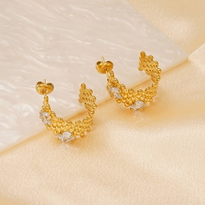 Macro detail of gold C-shaped earrings featuring textured mesh and square zircon stones