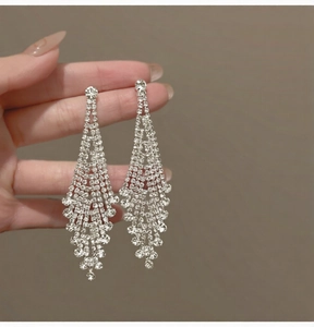 Close-up of sparkling silver tassel earrings with crystal rhinestones held by hand