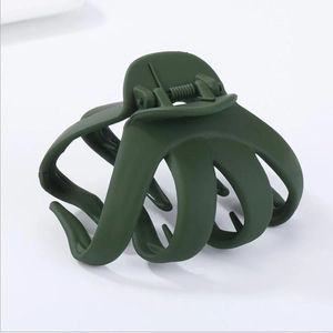 Detailed close-up of a dark green octopus-style hair claw with an irregular geometric shape