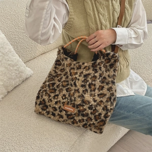Détail du sac cabas en peluche léopard avec des poignées tissées sur un canapé