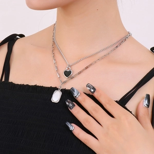 Detail of silver double-layered necklace with black heart and oval pendants on neck