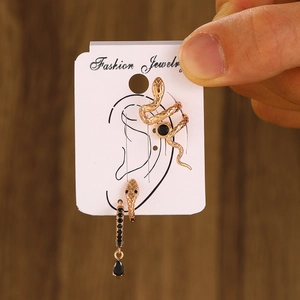 Detailed view of gold snake ear cuff and black gemstone pendant set on jewelry card