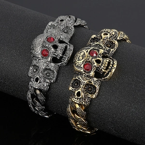 Detail of punk skull bracelets with red crystal eyes on silver and gold Cuban links