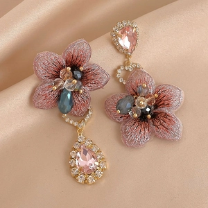 Détail de boucle d'oreille fleur brodée main avec dégradé violet et cristaux brillants