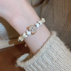 Close-up of minimalist beaded dog bracelet with bone charms on a cozy knit sleeve