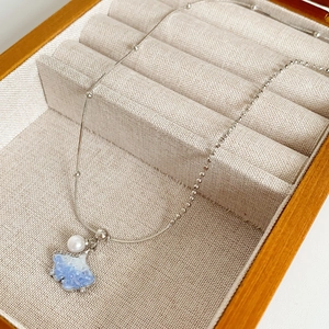 Macro detail of silver ginkgo leaf pendant with blue crystals and white pearl