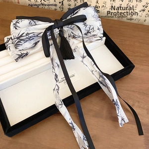 Close-up of bow hair clip with ink bamboo patterns, long tassels and black silk ribbons