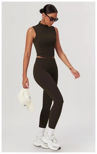 Full body shot of a model wearing dark high-waist yoga pants and sleeveless crop top