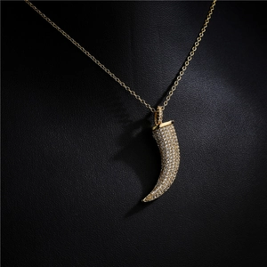 Collier corne dorée avec pendentif en zircons pavés sur présentoir en cuir noir