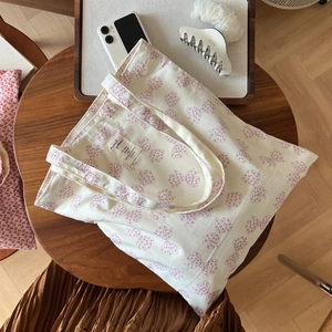 Détail d'un sac fourre-tout en coton crème avec motif nœuds violets sur table bois