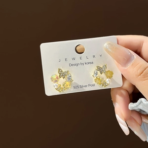 Detailed close-up of golden butterfly earrings with pearls and 925 silver posts
