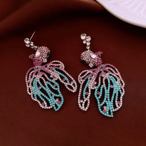 Vue détaillée des boucles d'oreilles poisson avec cristaux colorés sur fond velours