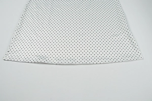 Close-up of white and black polka dot fabric hem showing clean stitching and soft drape