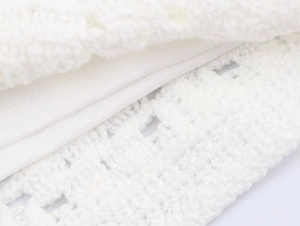 Detailed close-up showing the intricate white crochet texture and smooth inner lining fabric