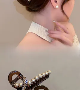 Detail of elegant amber acrylic hair claw clip with pearls and rhinestones on model