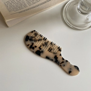 Detail view of portable tortoise shell acetate hair comb on an open book surface