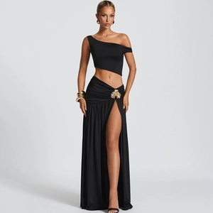 Detail of black two-piece set with one-shoulder top and maxi skirt featuring gold flower buckle