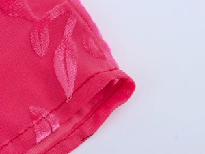 Gros plan du tissu jacquard rose avec motifs de feuilles et détails de couture