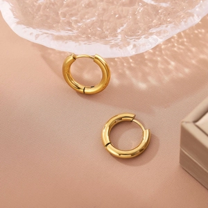 Polished 18K gold stainless steel hoop earrings on a decorative glass dish with a gift box