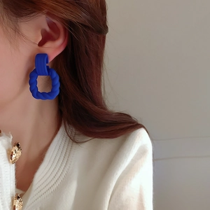 Detail of Klein blue twisted hoop earrings worn by a model in a modern style