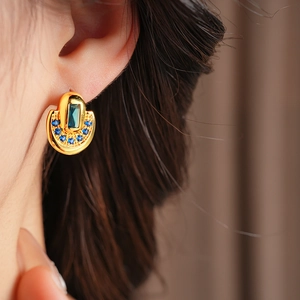 Gros plan de boucles d'oreilles vintage dorées avec pierres précieuses bleues sur modèle