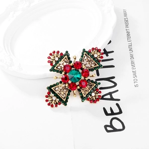 Close-up of vintage cross brooch with red and green crystals and golden filigree