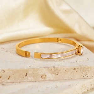 Detail of gold-plated stainless steel bracelet with white shell inlay and square zircon