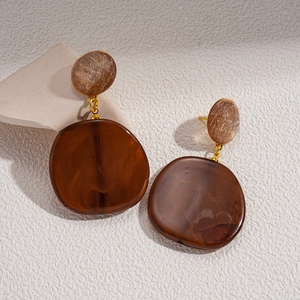 Macro view of geometric resin drop earrings with tortoiseshell texture and gold studs