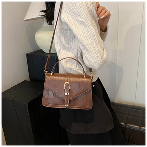 Detail of dark brown retro crossbody bag with textured leather and gold horseshoe buckle