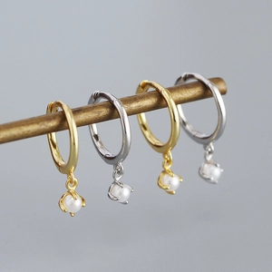 Detailed view of elegant pearl drop earrings hanging on a vintage bronze jewelry stand