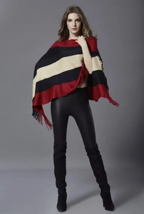 Close-up of knit poncho featuring red and black color-block stripes with fringed edges