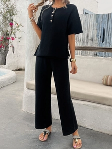 Close-up of black short-sleeved knit top with button neckline detail and matching trousers