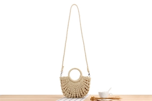 Detail of minimalist cream straw bag with unique semi-circle design and round handle