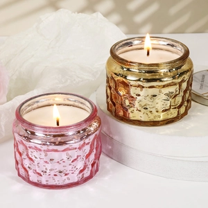 Embossed glass jar scented candles in gold and purple with decorative relief patterns