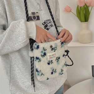 Detail of plush floral crossbody bag with woven strap and colorful square label