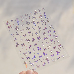 Detail showing 3D laser bow nail stickers with pearl accents on glossy adhesive sheet