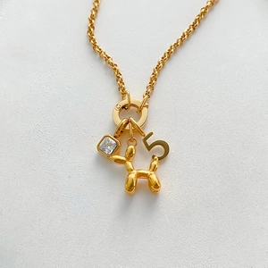 Detailed view of gold plated stainless steel necklace featuring balloon dog and number charms