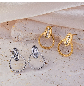 Detail of gold and silver twist hoop earrings with four-diamond inlay on silk background