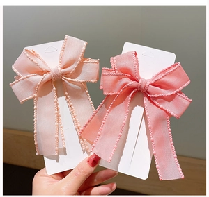 Detailed close-up of pink chiffon bow hair clips with delicate beaded wavy edges