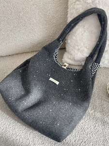 Borsa tote in feltro grigio con stelle e fodera a quadretti su divano beige