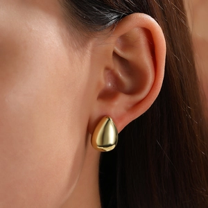Macro shot of minimalist teardrop earrings in polished 18k gold plating on a model