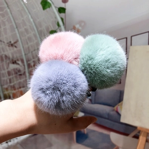 Close-up of soft faux fur pom pom hair ties in pink, mint green and lavender purple
