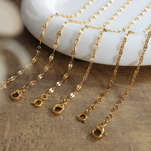 Golden titanium steel lip-link bracelet with lobster clasps displayed on a ceramic plate
